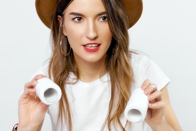 Niña feliz con sombrero con bobinas de hilos cerca de los ojos. Foto de alta calidad