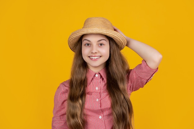 Niña feliz con sombrero de paja sobre fondo amarillo