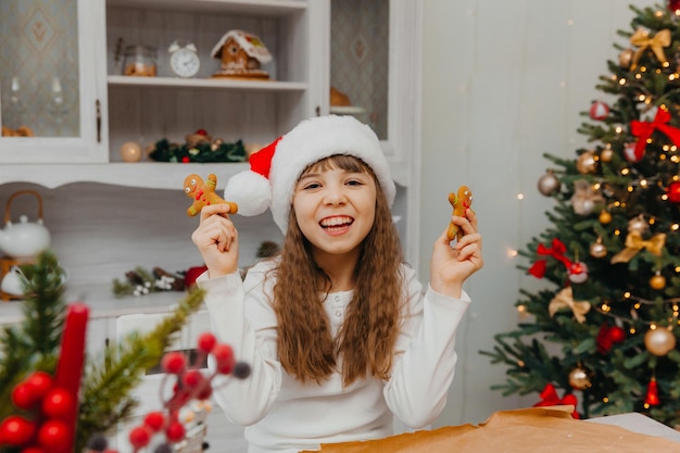 Niña feliz con sombrero de santa claus tiene hombres de pan de jengibre.