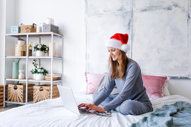 Niña feliz con sombrero de santa saluda a amigos feliz navidad chat de video en la computadora portátil