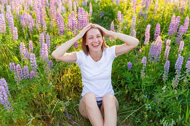 Niña feliz sonriendo al aire libre. Hermosa joven brunete descansando en el campo de verano con fondo verde floreciente de flores silvestres.