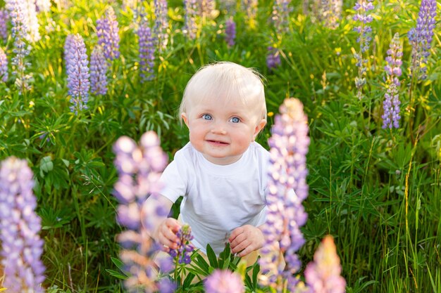 Niña feliz sonriendo al aire libre. Hermosa niña rubia joven descansando en el campo de verano con fondo verde de flores silvestres en flor