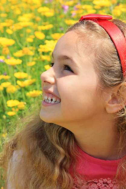 Niña feliz sonriendo en un jardín de flores amarillas