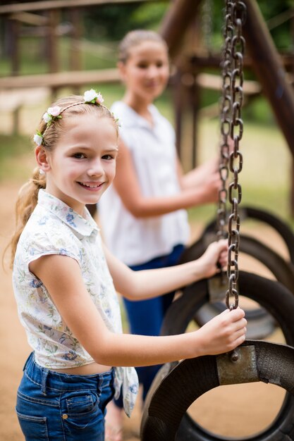 Niña feliz sonriendo mientras sostiene un columpio en el parque