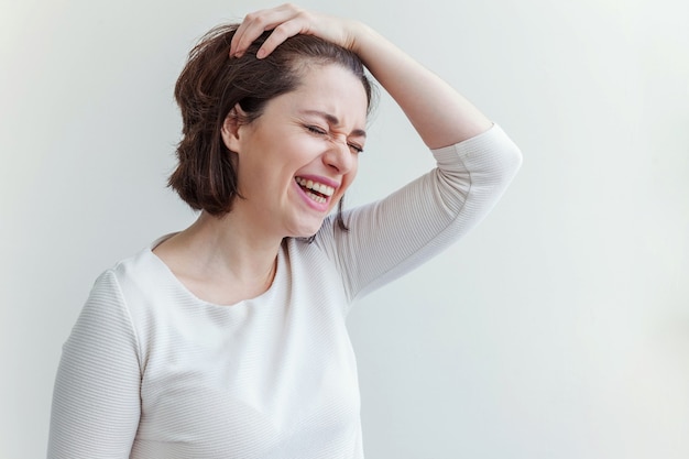 Niña feliz sonriendo. Retrato de belleza joven mujer morena riendo positivo feliz sobre fondo blanco aislado. Mujer europea. Lenguaje corporal de expresión facial de emoción humana positiva.