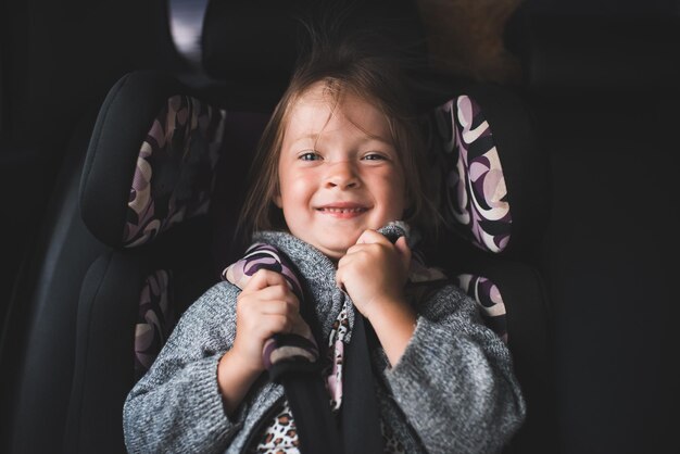 Niña feliz sonriente de 45 años sentada en el asiento del auto y viajando Cuidado de niños