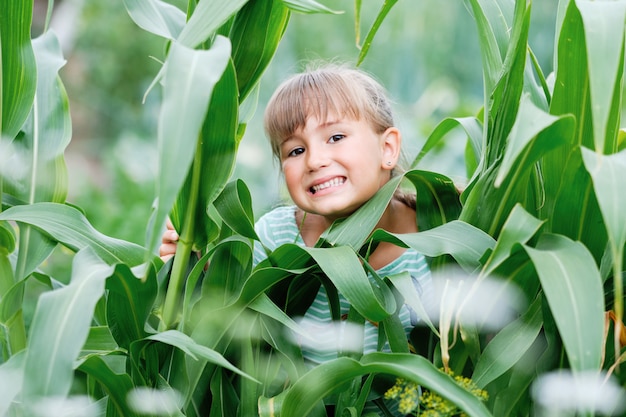 Niña feliz sonriente y hojas de plantas verdes