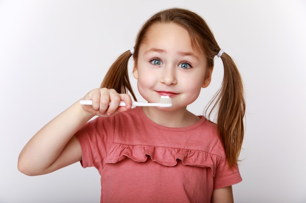 Foto niña feliz sonriente mientras se cepilla los dientes