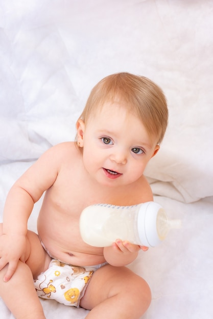 Niña feliz sosteniendo una botella de leche de comida para bebés