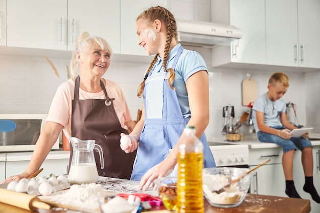 Niña feliz y su abuela sonriente posando en la cocina