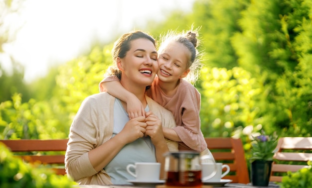 Niña feliz y su madre bebiendo té en una mañana de verano