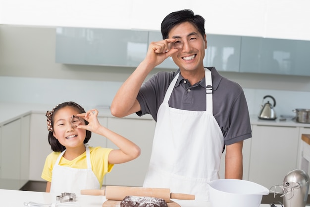 Niña feliz con su padre sosteniendo moldes de galletas en la cocina