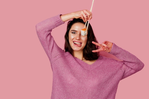 Foto niña feliz con sushi sobre fondo rosa