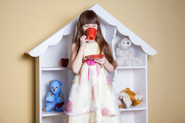 Niña feliz con una taza de té en su habitación