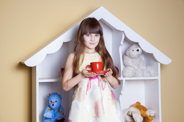 Niña feliz con una taza de té en su habitación