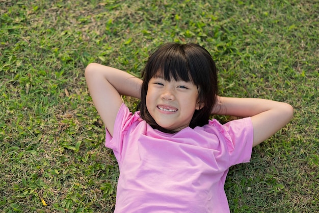 Niña feliz tirada en el patio de juegos de hierba