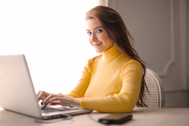 Niña feliz trabajando en una computadora portátil