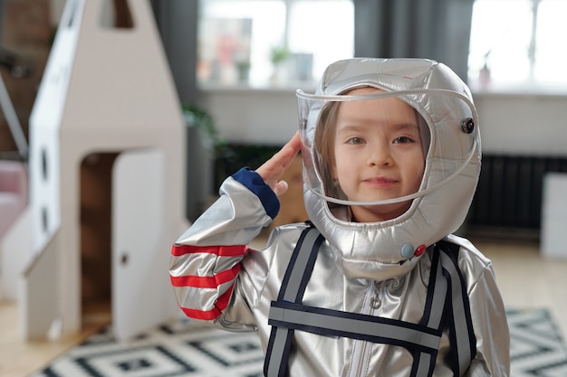 Foto niña feliz en traje espacial de pie en la sala de estar