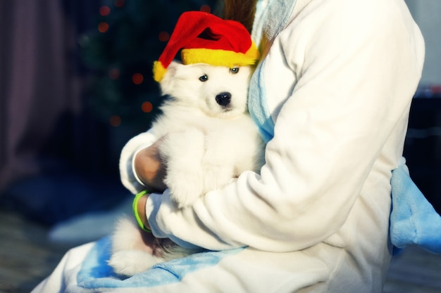 Niña feliz en traje de unicornio con perro husky samoyedo en adornos navideños