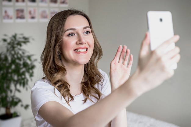 Niña feliz usa su teléfono móvil y hace videollamadas a amigos