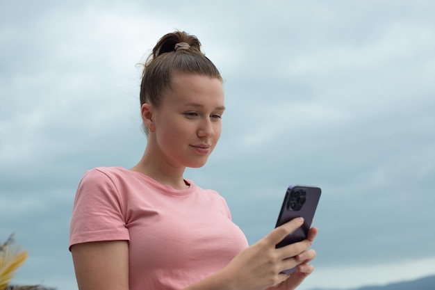 Niña feliz usa su teléfono en el techo de una casa balcón ciudad fondo mujer tomando selfie