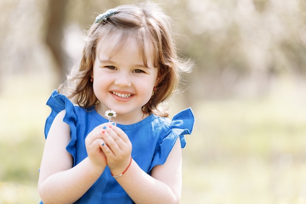 Niña feliz en un vestido azul juega con flores