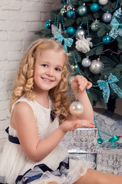 Niña feliz en un vestido con sus regalos de Navidad