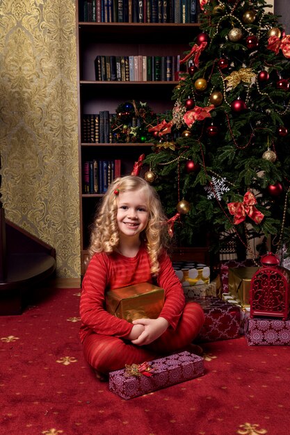 Niña feliz en un vestido con sus regalos de Navidad