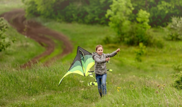 Foto niña feliz volando cometa brillante al aire libre en la naturaleza en primavera