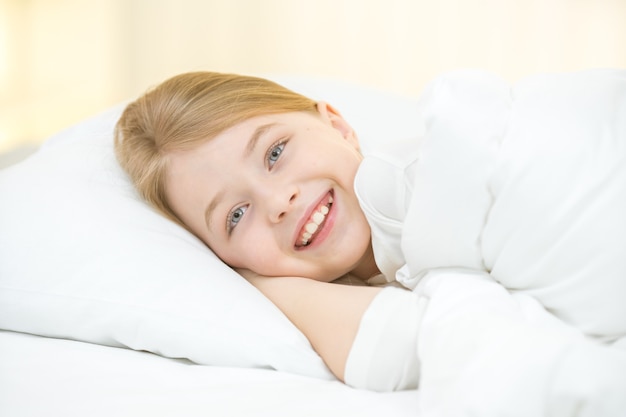 La niña feliz yacía en la cama