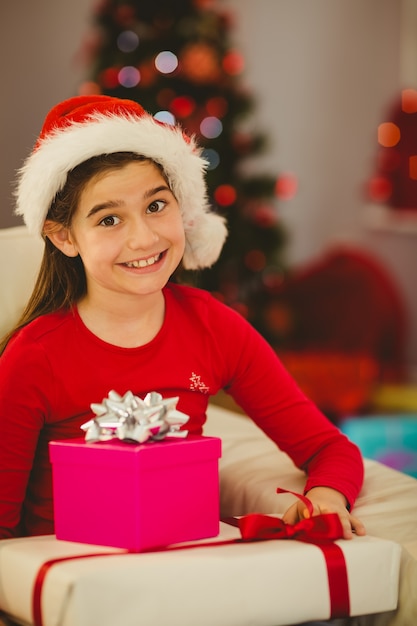 Niña festiva sonriendo a la cámara con regalos