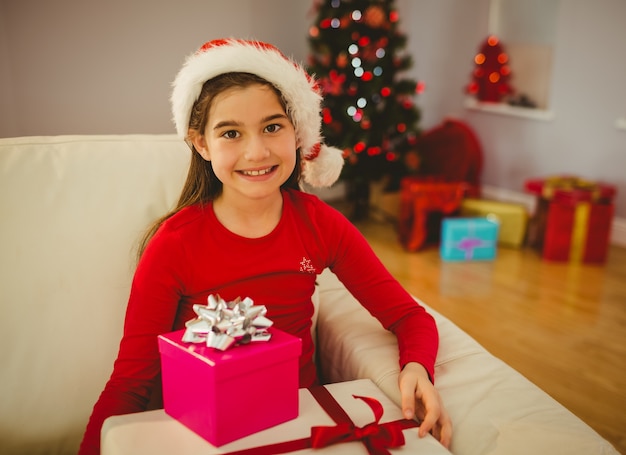 Niña festiva sonriendo a la cámara con regalos