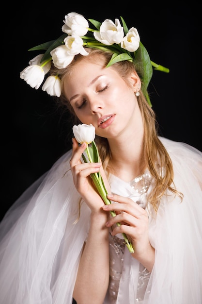 Niña con flores blancas en la cabeza y en las manos tulipanes blancos