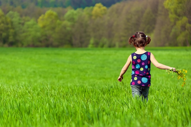 Niña con flores en campo verde