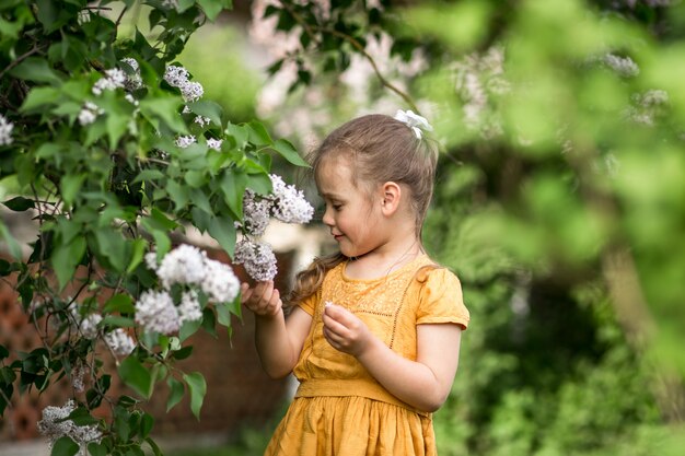 niña y flores lilas en el jardín en verano