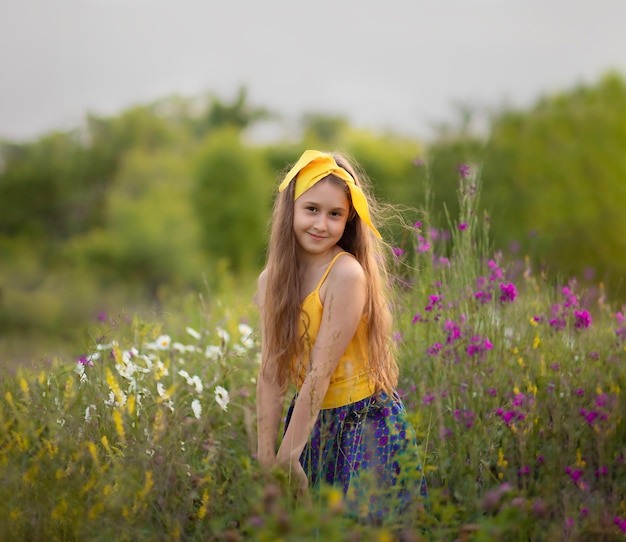 una niña se para entre las flores en un prado y sonríe