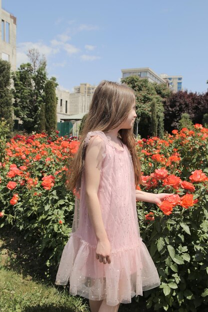 Niña entre flores de rosas naranjas