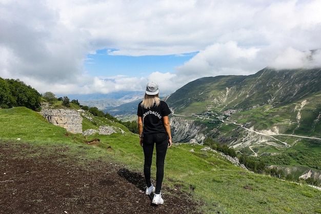 Una niña en el fondo de hermosas montañas verdes en Daguestán con nubes Rusia