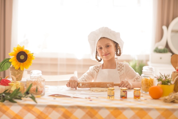 niña en forma de cocinero extiende la masa