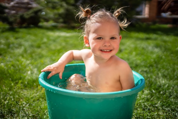 Una niña fracasa en un lavabo con agua en el patio trasero de su casa en verano