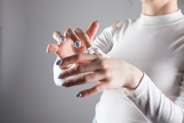 Niña se frota las manos con crema en una escena gris