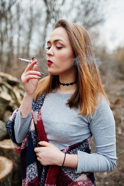 Niña fumando cigarrillos en el bosque