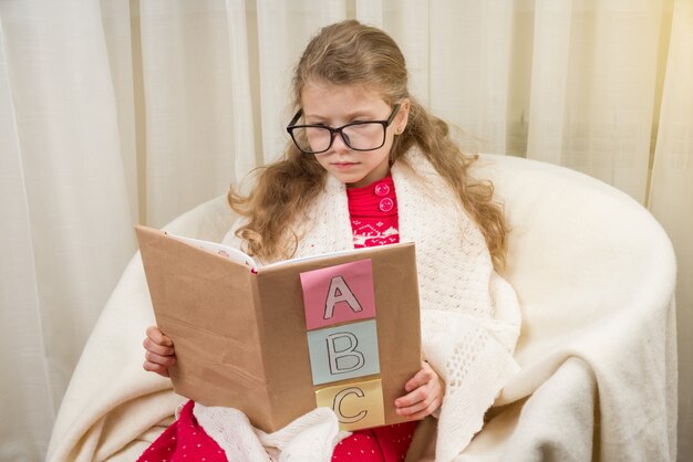 Niña con gafas aprende a leer un libro