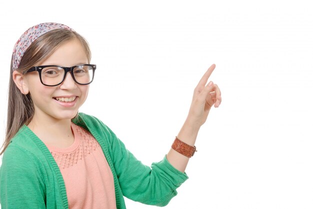 Niña con gafas, apuntando con su dedo, sobre fondo blanco.