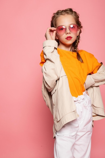 Niña en gafas de color rosa Estilo de moda de moda concepto de tiempo de diversión con estilo Retrato de cuerpo entero de tamaño completo vertical de risa linda dulce adorable encantadora encantadora niña aislada fondo rosa