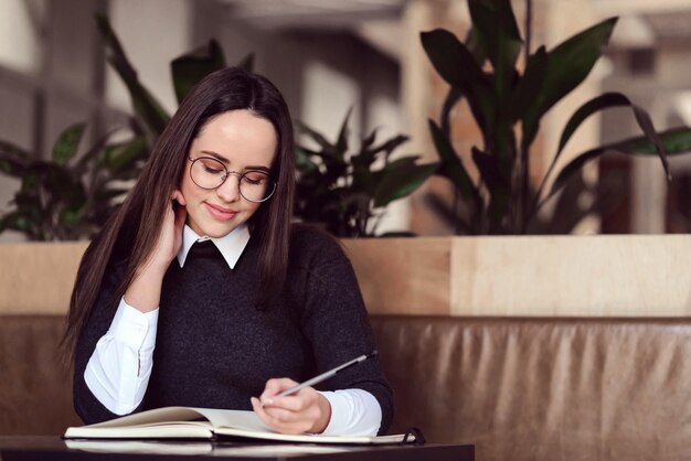 Niña con gafas escribiendo algo en su cuaderno