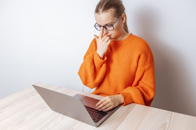 Una niña con gafas está sentada frente a una computadora portátil