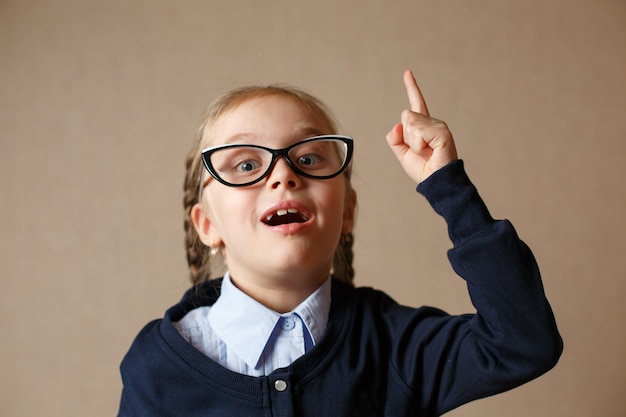 Una niña con gafas levantó el dedo. Concepto de la idea