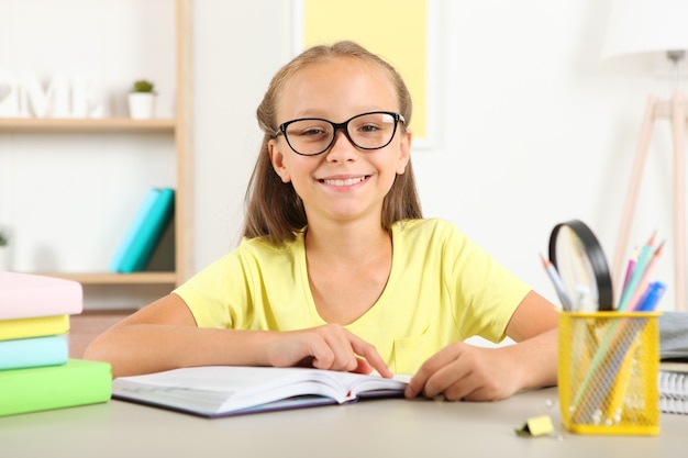 Niña con gafas leyendo un libro en casa