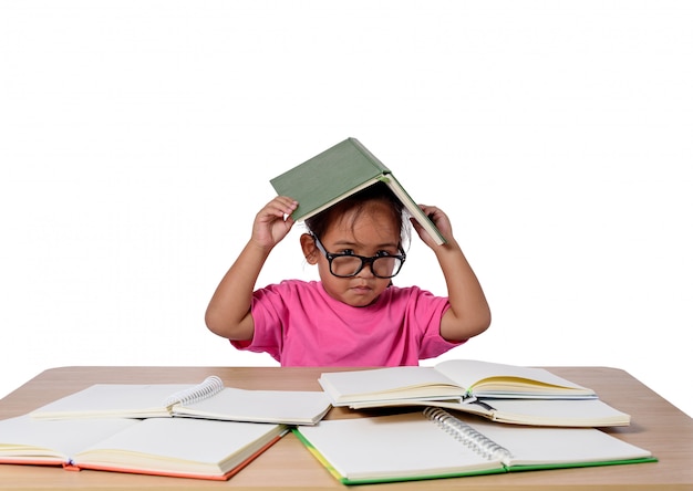 Niña con gafas de pensamiento y muchos libros sobre la mesa. Volver al concepto de escuela, aislado sobre fondo blanco